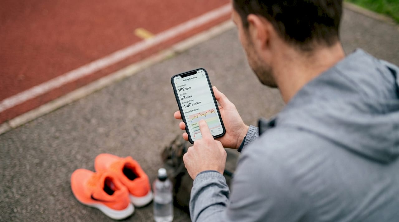 Athlete viewing fitness data at running track